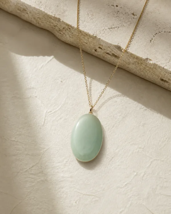 Pale green jade pendant on an ivory surface
