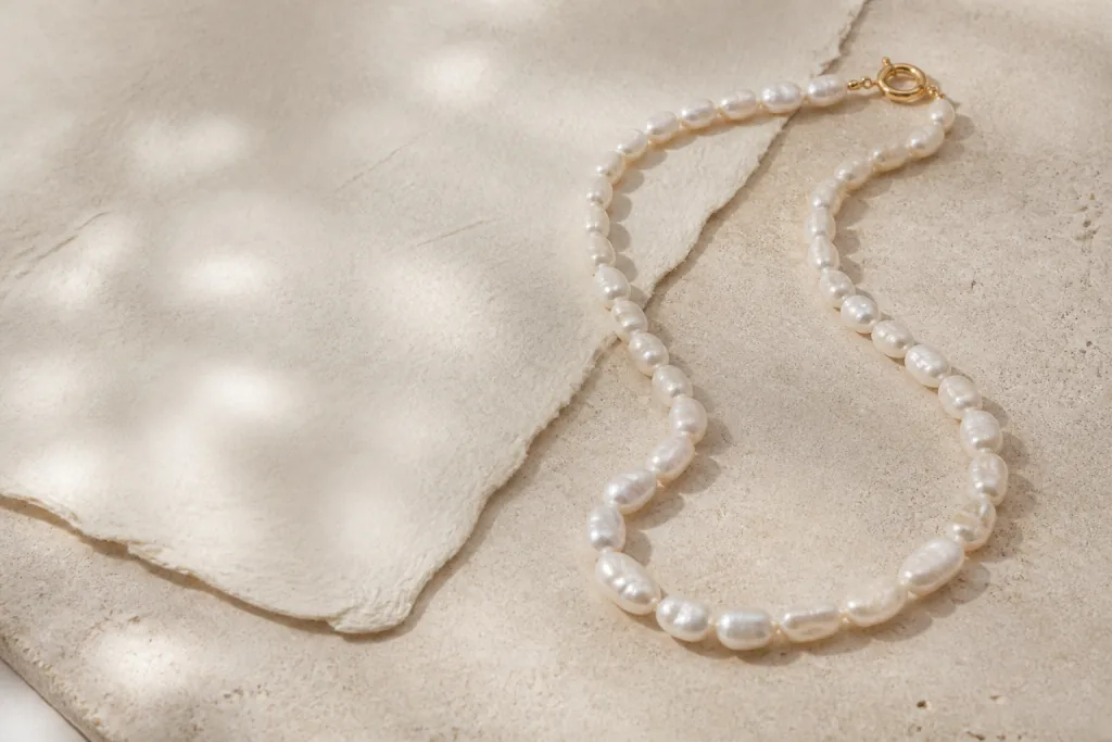 Irregular freshwater pearl necklace with a gold clasp on warm stone